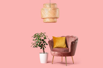 Cozy armchair with cushion near houseplant on pink background