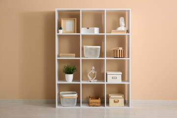 Fototapeta premium Shelving unit with decoration near beige wall