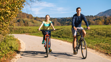 Young couple enjoying pleasant cycling in beautiful countryside during fall weekend trip. Leisure and outdoor activity concept.