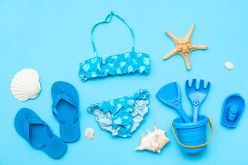Beach accessories for children, kid's flip-flops and swimsuit on blue background. Top view