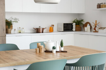 Teapot with plants and candles on dining table in kitchen