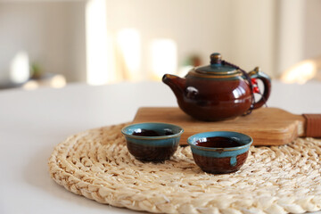 Teapot with cups on dining table in room, closeup