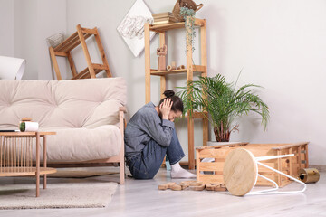 Young woman hiding near sofa during earthquake at home