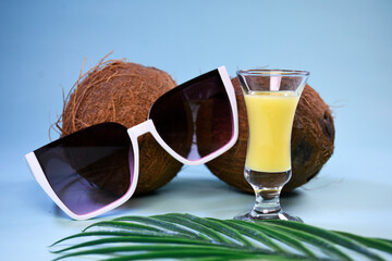 Sunglasses and a glass of liquor on a coconut background