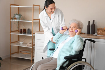 Obraz premium Physical therapist and senior woman in wheelchair with dumbbells training at home