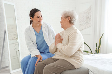 Fototapeta premium Physical therapist with senior woman sitting in bedroom
