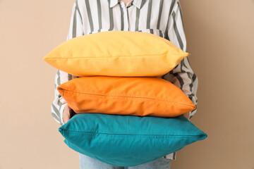 Woman with bright pillows on beige background, closeup