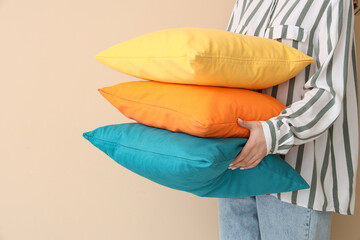 Woman with bright pillows on beige background, closeup