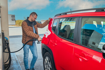 Man filling benzine gasoline fuel in car at gas station. Man refueling car.