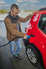 Man filling benzine gasoline fuel in car at gas station. Man refueling car.