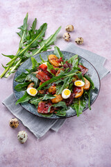 Traditioneller Südtiroler Löwenzahnsalat mit Frühstücksspeck, Bratkartoffel und Wachteleier serviert als Nahaufnahme auf einem Nordic Design Teller