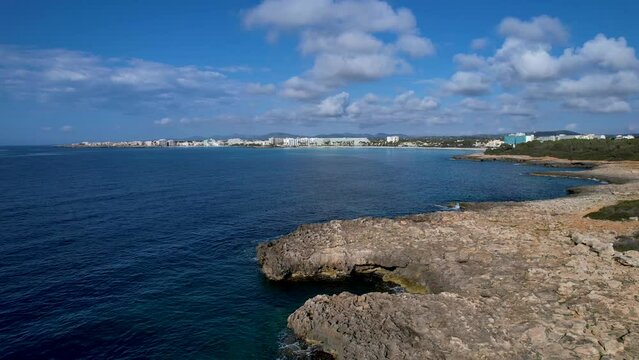 4K Aerial Drone video of the rocky coast with crystal clear water in Mallorca with rough waves crashing against the cliffs on a sunny summer day