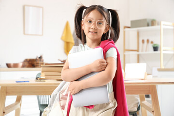 Little Asian girl with laptop in kitchen