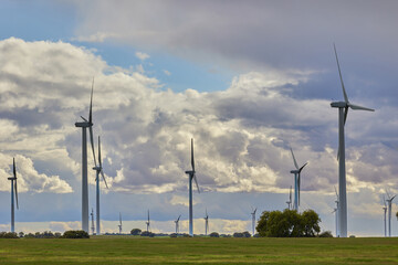 Wind turbines in an agricultural field against cloudy sky