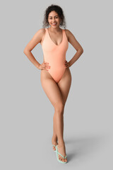 Fototapeta premium Beautiful young African-American woman in stylish swimsuit on grey background