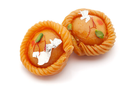 Two pieces of Indian traditional sweet "Chandrakala", filled with dry fruits. Front view. Isolated on a white background.