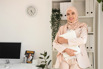 Beautiful Muslim businesswoman with folder in office