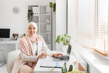 Beautiful Muslim businesswoman working with laptop at desk in office