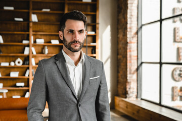 Cropped portrait of young businessman in formal suit looking at the camera in modern office. CEO...