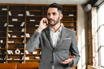 Busy young manager talking on cellphone in modern office. Businessman CEO lawyer solicitor selling...