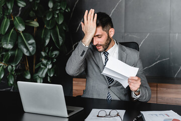 Confused young businessman having financial problems with debts in office. Manager CEO having...