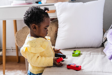 A young girl is playing with a toy car on a bed
