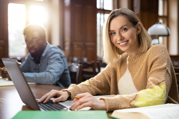Blonde smiling woman at the laptop in the library