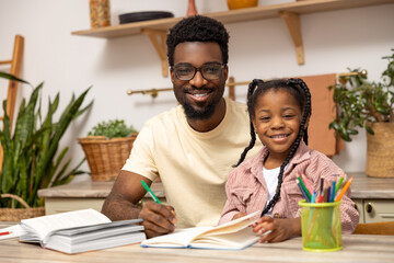 Happy father helping schoolgirl daughter studying