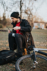 Focused young man pauses from cycling, he is using duct tape while sitting next to his bicycle in a serene park setting as the sun sets.