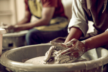 Close up of sculptors hands working with clay on a pottery wheel