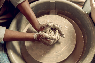 Close up picture of hands working with wet clay and molding its shape