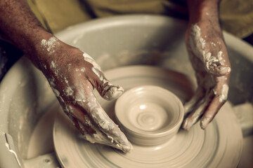 Close up picture of hands working with wet clay and molding its shape