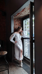 a beautiful woman with dark hair, wearing a long white dress  in a city street cafe. happy people