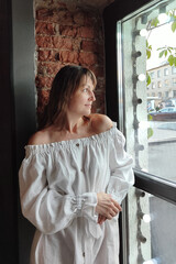 Fototapeta premium a beautiful woman with dark hair, wearing a long white dress in a city street cafe. happy people