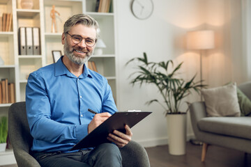 Happy male psychologist with clipboard looking at camera and smiling