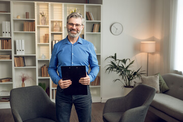 Happy male psychologist with clipboard looking at camera and smiling
