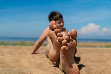 Closeup of a boys feet on the beach with sand