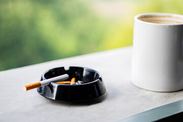 Coffee mug and ashtray on ledge with scenic background
