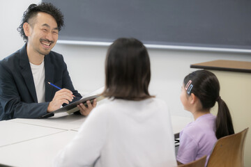 面談を受ける親と子供　三者面談のイメージ　親子の顔無しのイメージ