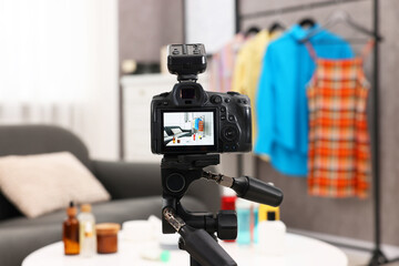 Beauty blogger's workplace. Cosmetic products and clothes indoors, focus on camera