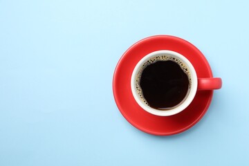 Aromatic coffee in cup on light blue background, top view. Space for text