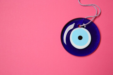 Evil eye amulet on pink background, top view. Space for text