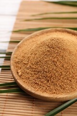 Coconut sugar, palm leaves and bamboo mat on table, closeup
