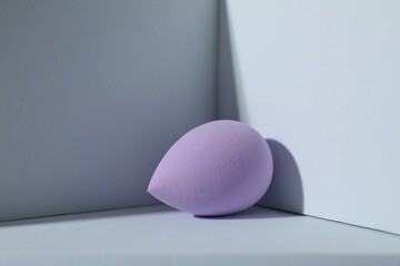 One violet makeup sponge on light background