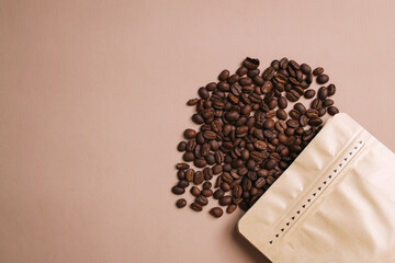 Spilled Out Coffee Beans With Blank Eco Packaging Over Beige Background