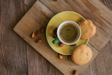 Coffee in green cup with cookies on the wooden table. Rustic wooden background. Cozy morning Breakfast at home or in a cafe.