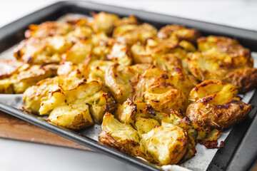 smashed baby potatoes on oven tray with rosemary and herbs