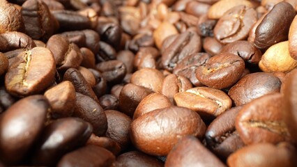 Luxuriously dark coffee beans, glistening with oil, boast an intense roast. Their intricate textures and delicate cracks unveil the artistry behind their creation, promising a deeply flavorful brew.
