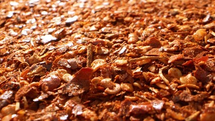 Vivid and fiery, this close-up reveals ground chili in all its glory: a mosaic of fiery red flakes and seeds, boasting a coarse texture that promises an explosion of spicy flavor.
