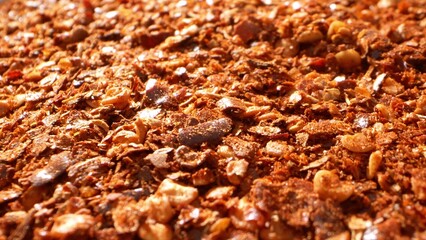 Zoom in on ground chili, showcasing fiery red flakes with specks of seeds and dried skin. Coarse texture accentuates vivid red-orange tones, embodying the essence of chili powder.
